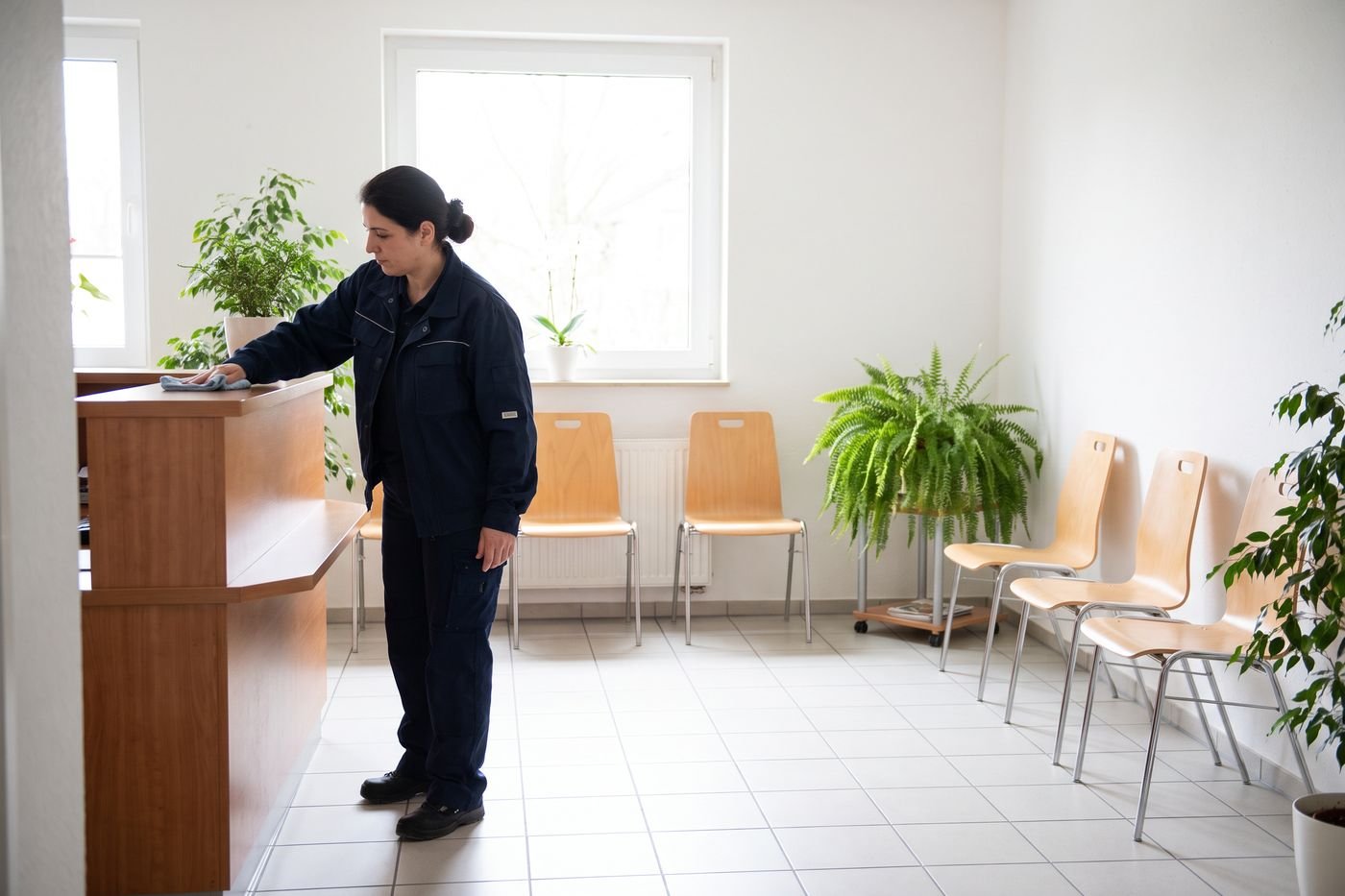 Reinigungskraft wischt den Empfangstresen einer Arztpraxis
