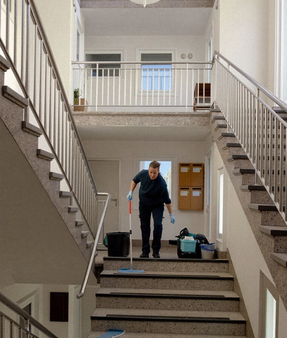 Reinigungskraft wischt das Treppenhaus eines Mehrfamilienhauses
